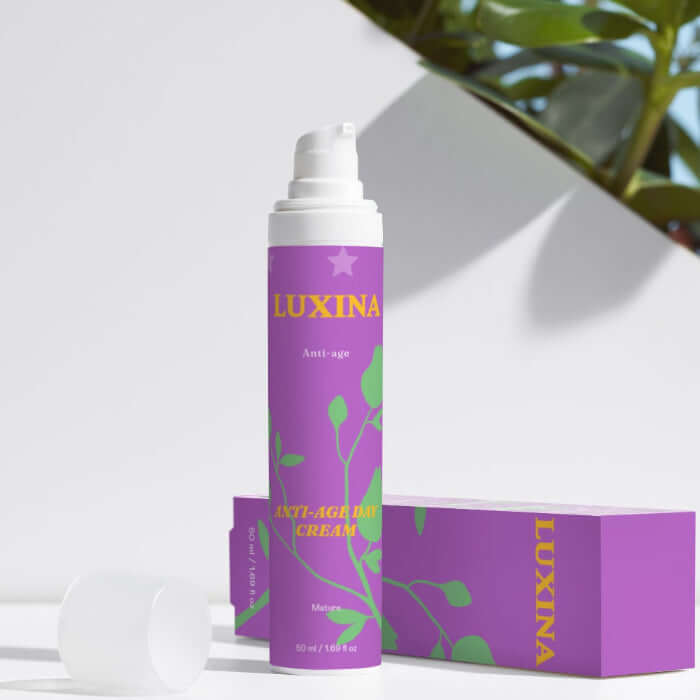 Luxina cream tube and packaging on a white surface with green leaves in the background