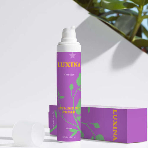 Luxina cream tube and packaging on a white surface with green leaves in the background
